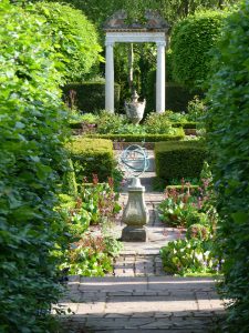 An armillary sphere on a sundial plinth in a beautiful garden design.