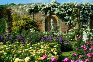 A garden bursting with blooms with a statue as a classical focal point.