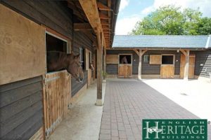 Horse stables with traditional staddle stones and horse looking out of window