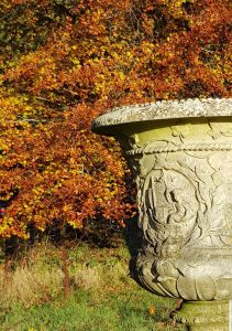 An ornate and decorative Chilstone urns makes a beautiful stand out garden features against the backdrop of bright autumn trees.